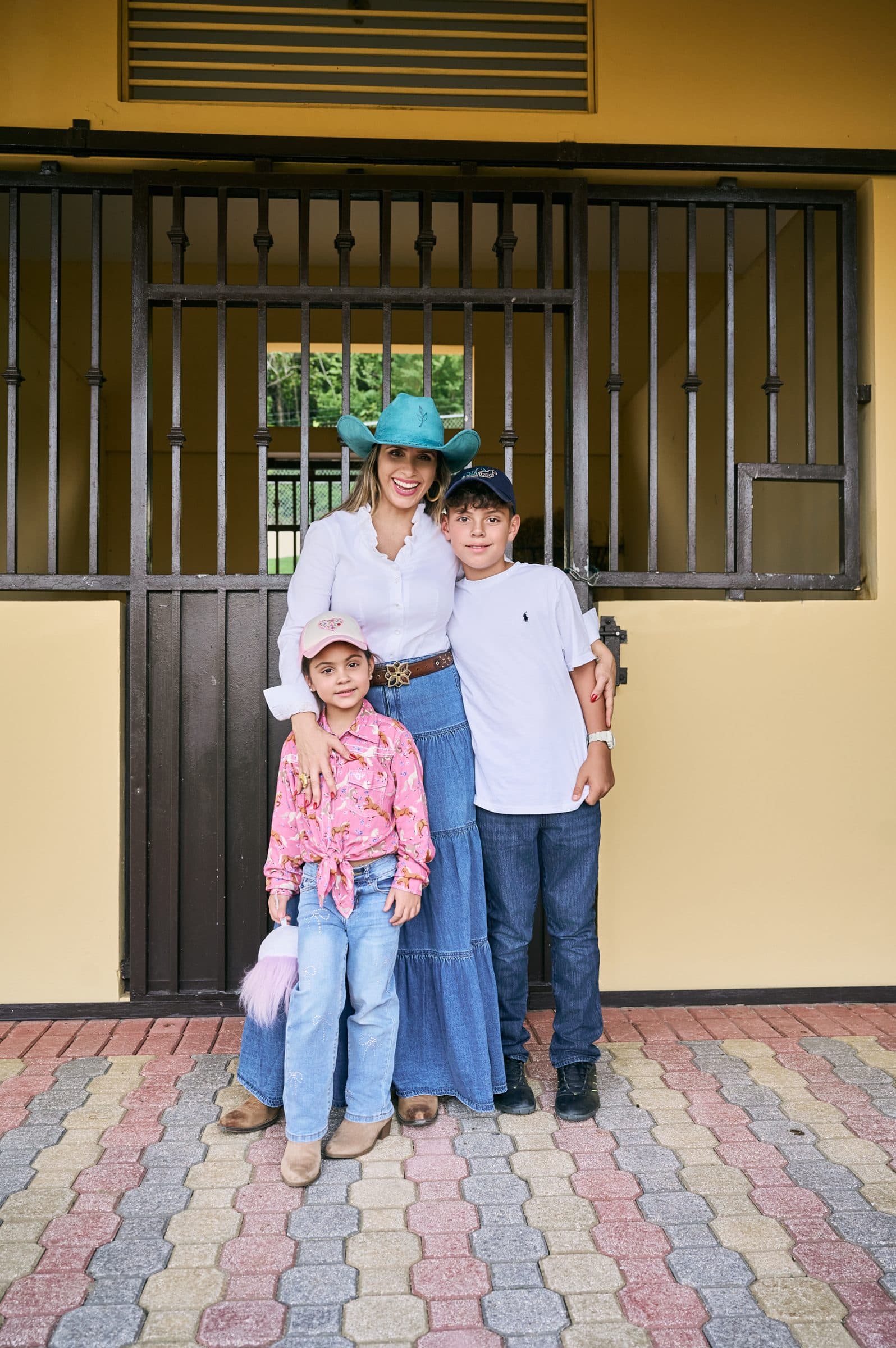 La Dra. Najul posando con dos niños frente a las caballerizas