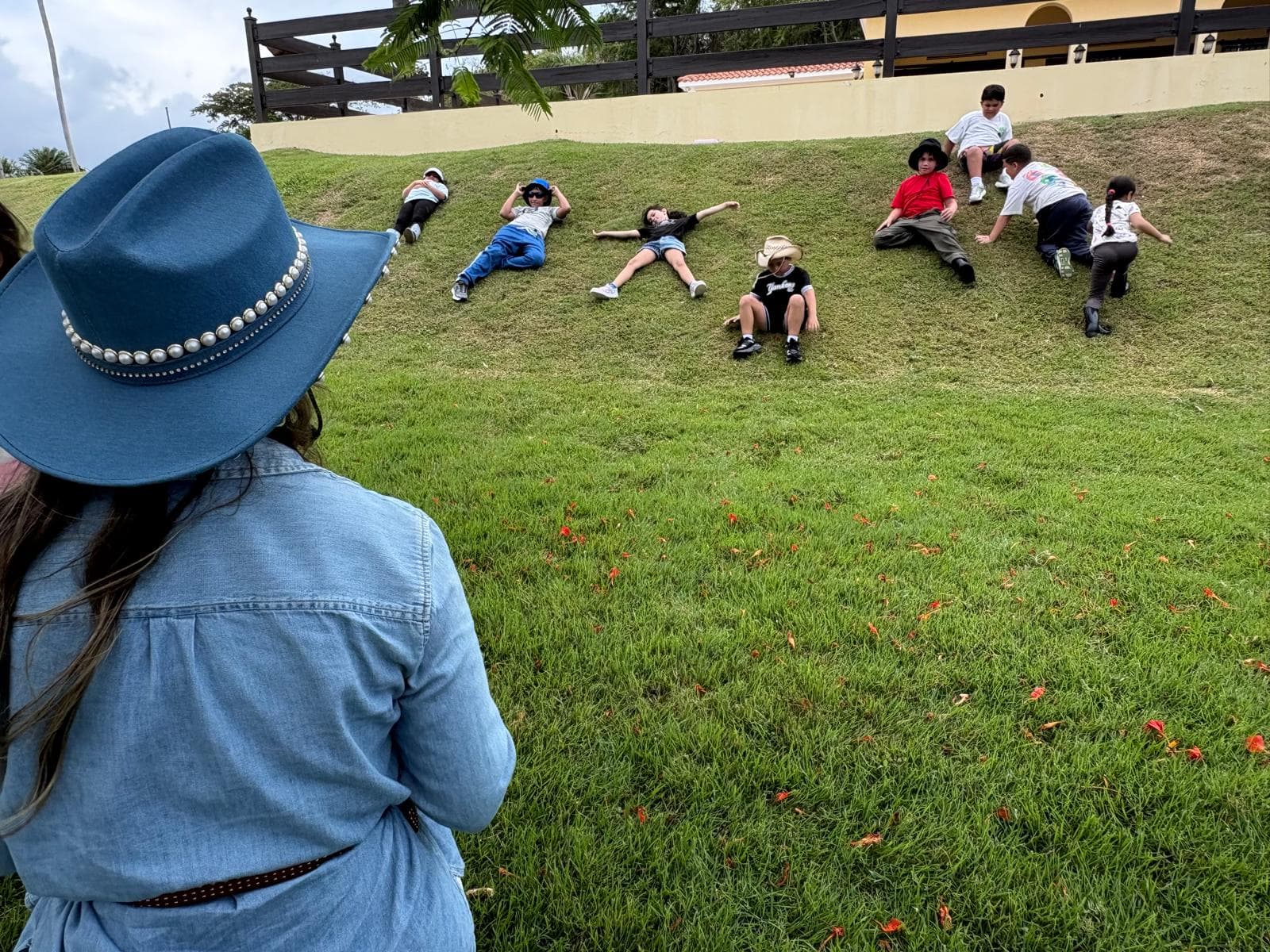 Niños descansando sobre la grama mientras una facilitadora los acompaña