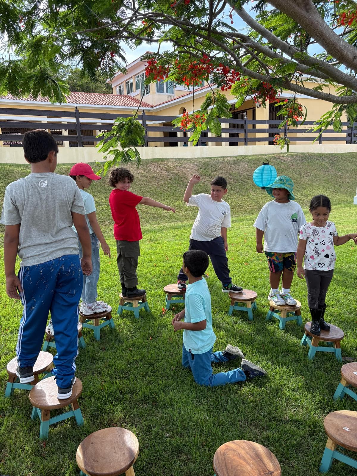 Niños jugando de pie sobre banquitos de madera en el jardín