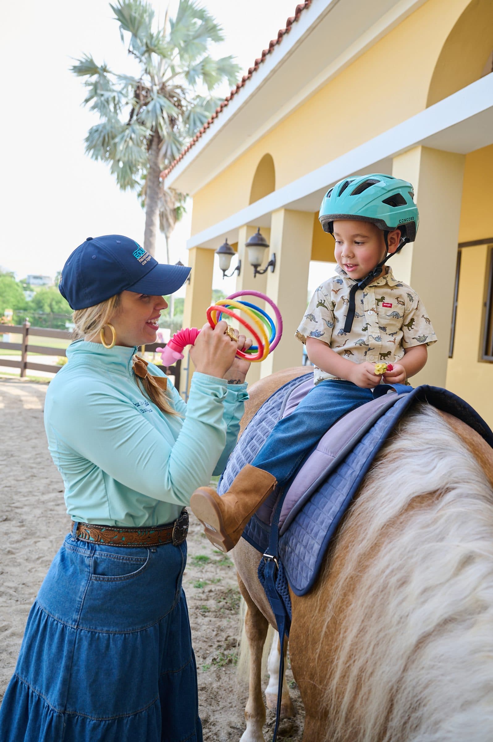 Terapeuta y niño a caballo trabajando con aros de colores